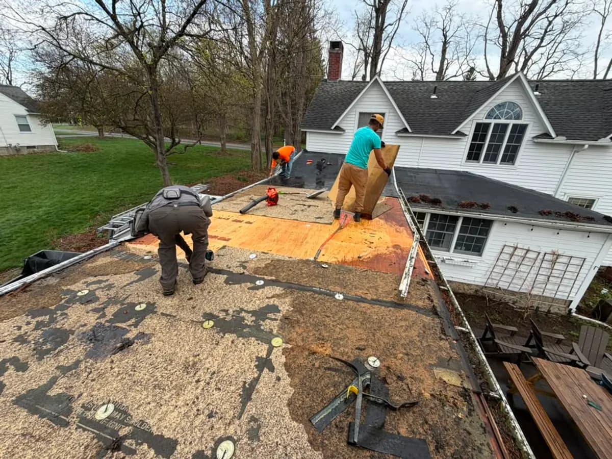 Roofers fitting new sheathing panels on a roof deck