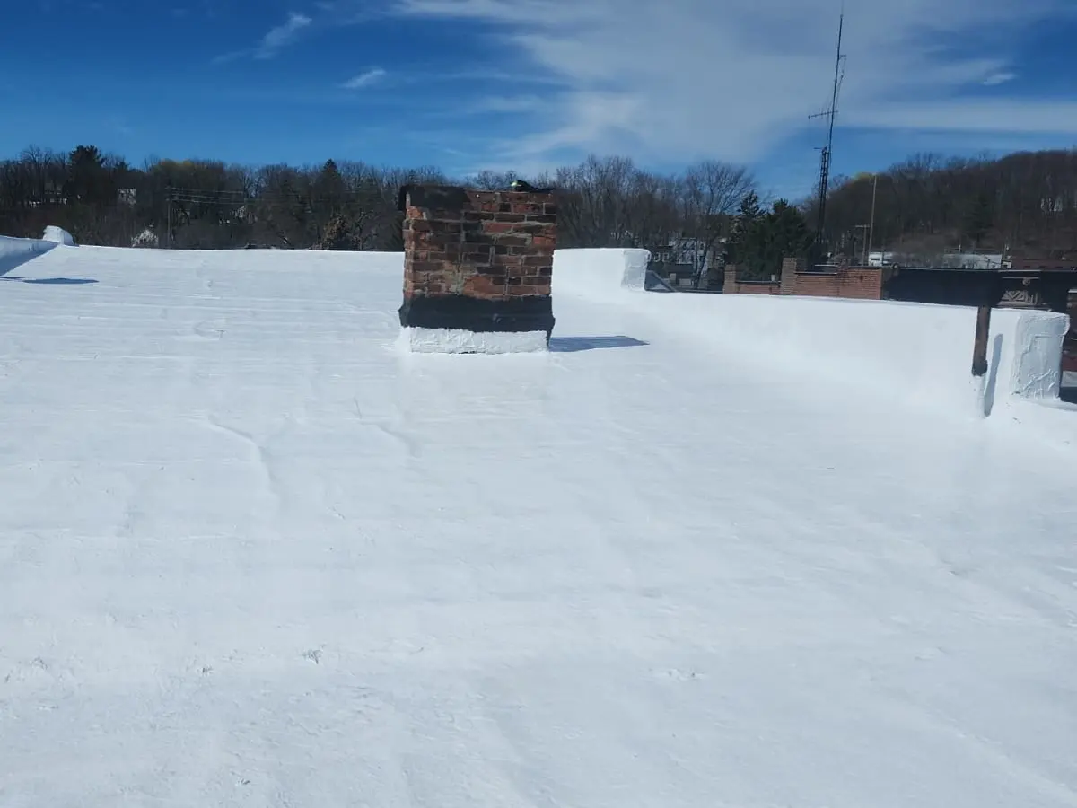 Low-slope roof coated white, overlooking a row of brick buildings