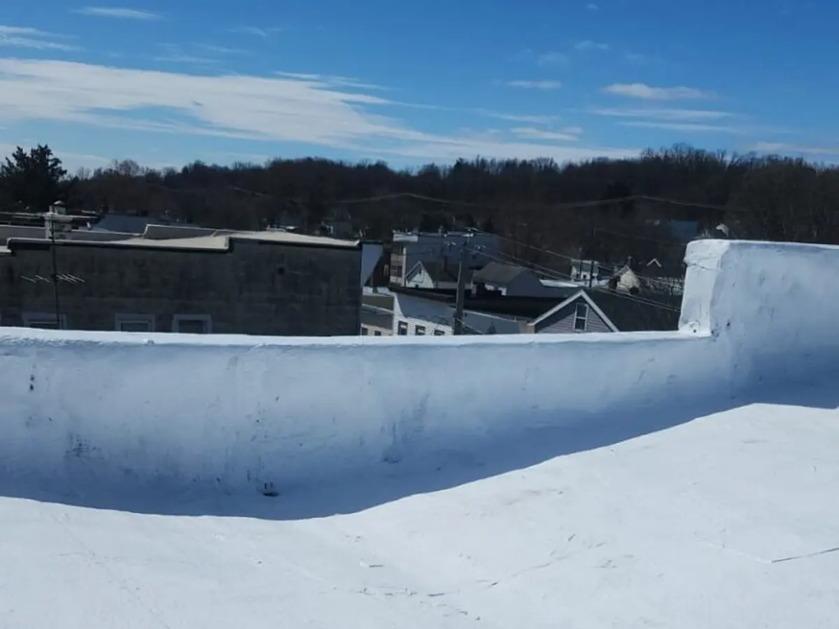 Wide flat roof finished in white membrane above a residential street