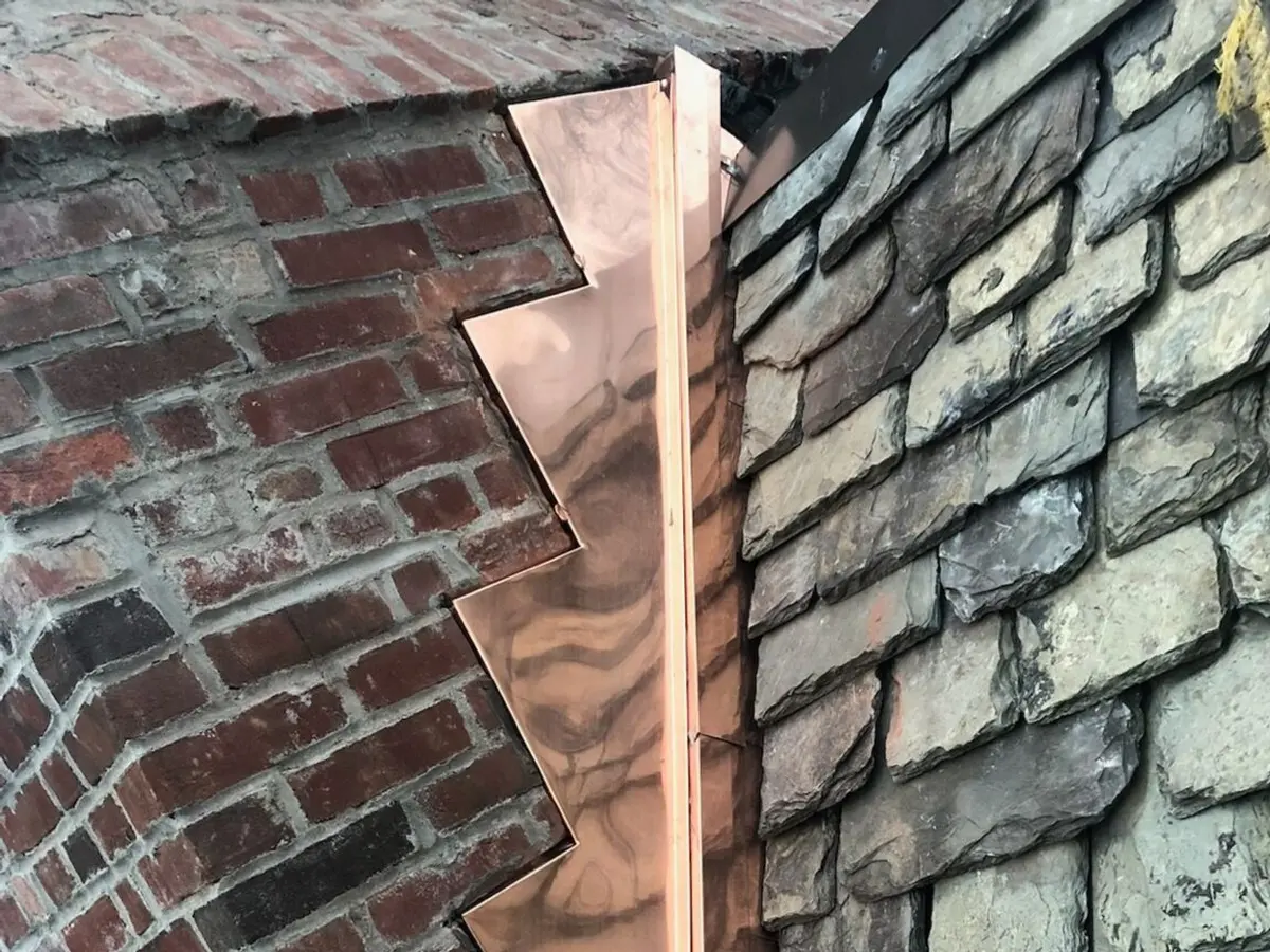 Close view of copper flashing worked into brickwork and slate