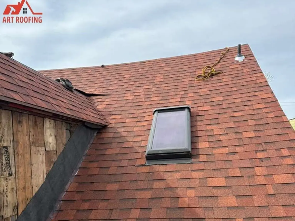 Red-brown shingle roof with a skylight, freshly completed on a older home