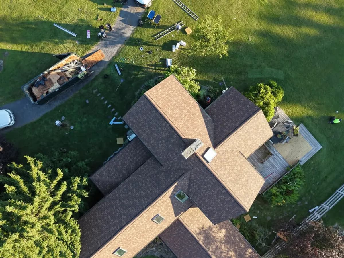 Aerial view of a completed brown shingle roof on a multi-gable house
