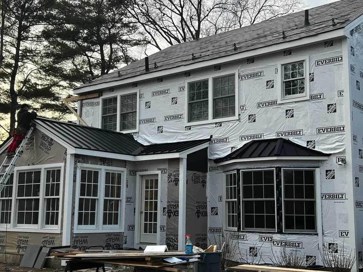 Home wrapped in weather barrier mid-project, new windows already fitted