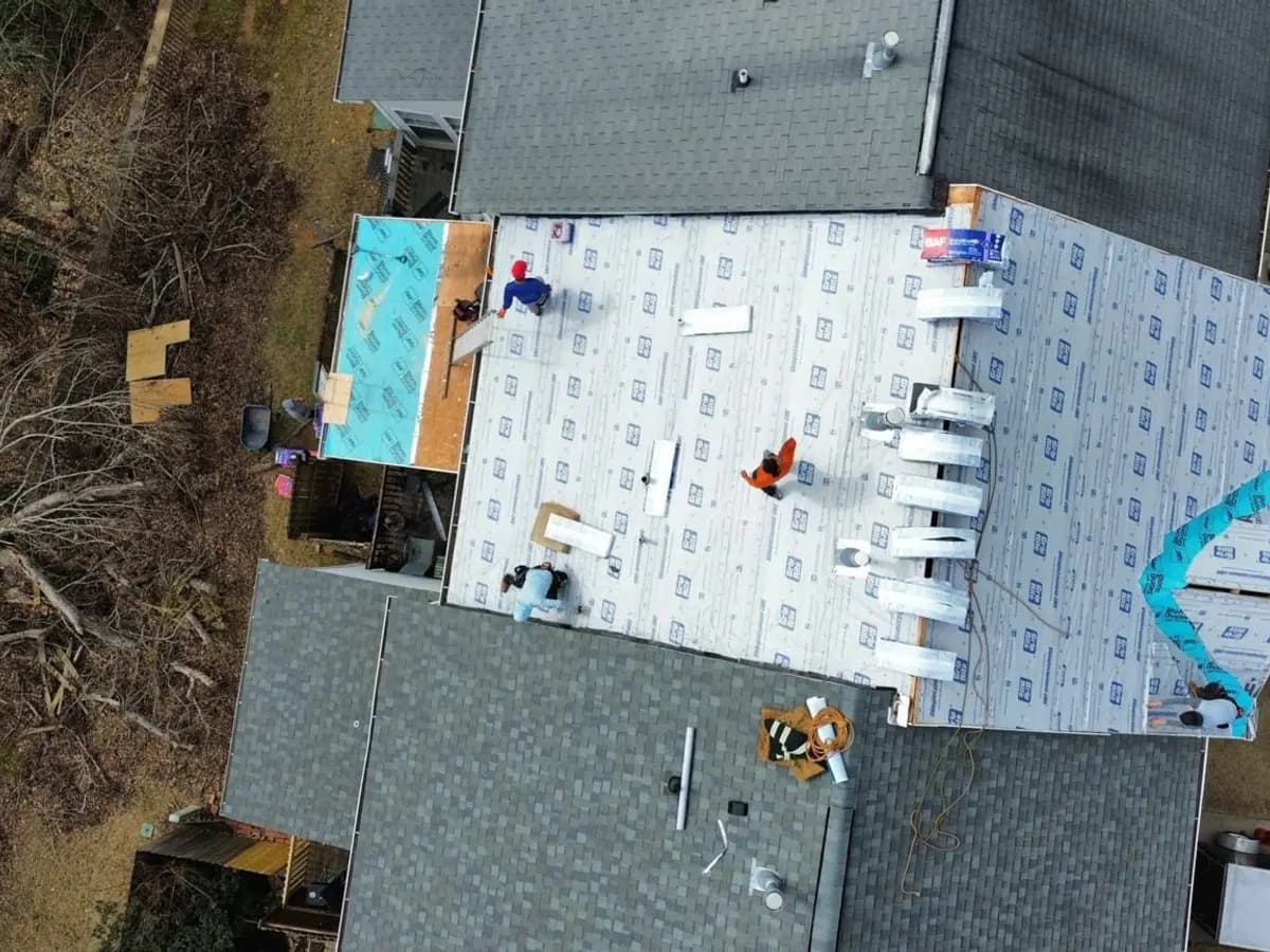 Aerial view of a roof mid-repair with tarps protecting the opened sections
