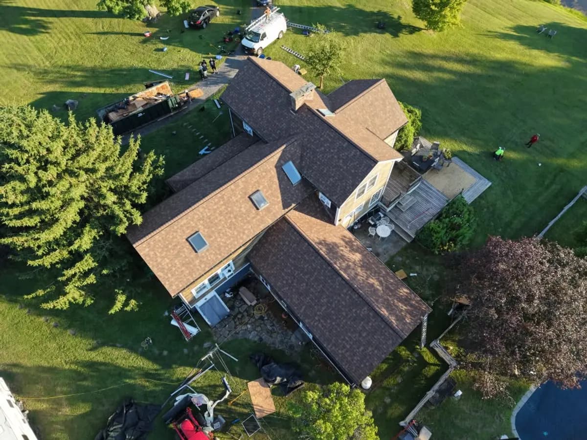 Aerial view of a house with tarped roof sections awaiting insurance repair